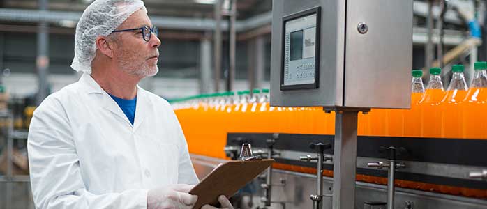 A man with a clipboard looking at the screen of industrial machinery