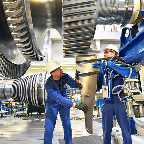Two people working on an engine turbine