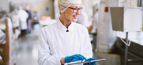 A smiling factory worker with a clipboard