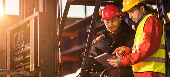 Two men near a forklift looking at a tablet device