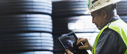 Man standing in front of a stack of tires using a tablet device