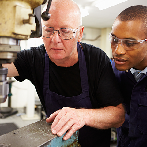 Two people working, one is training the other on how to use a piece of machinery