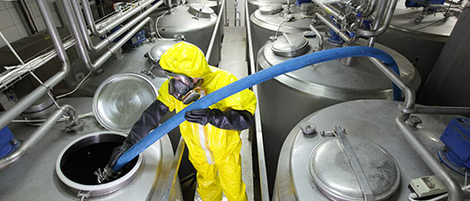 A person in a hazmat suit cleaning large tanks