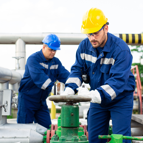 Two men in hard hats operating a pipeline.