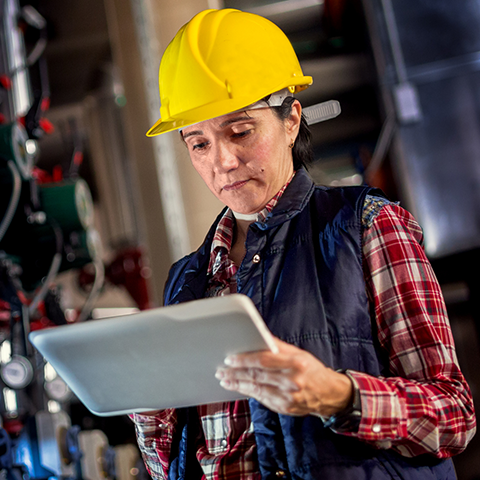 A woman in a hardhat using a tablet device.