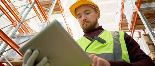 A man in a warehouse using a tablet device.