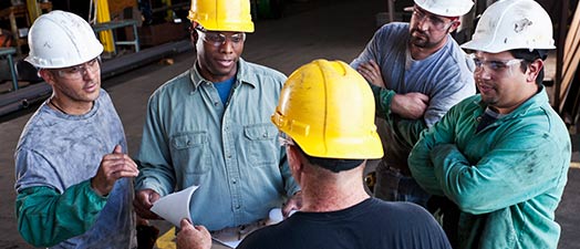 Five people in hard hats talking.