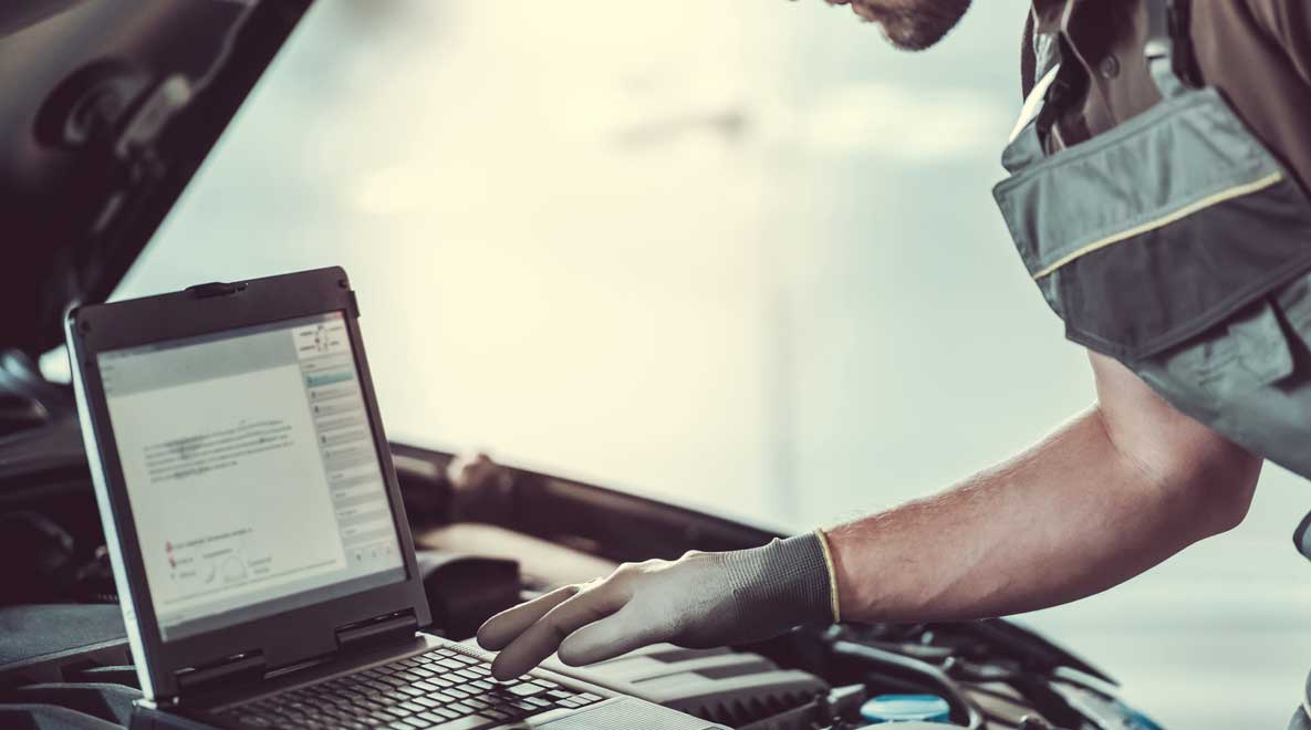 A man using a computer to tune a car.