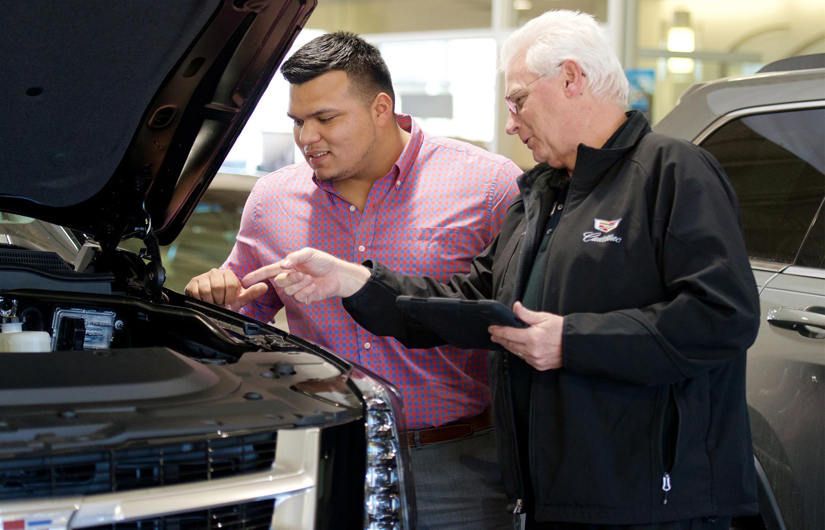 Two men looking under the hood of a pickup truck